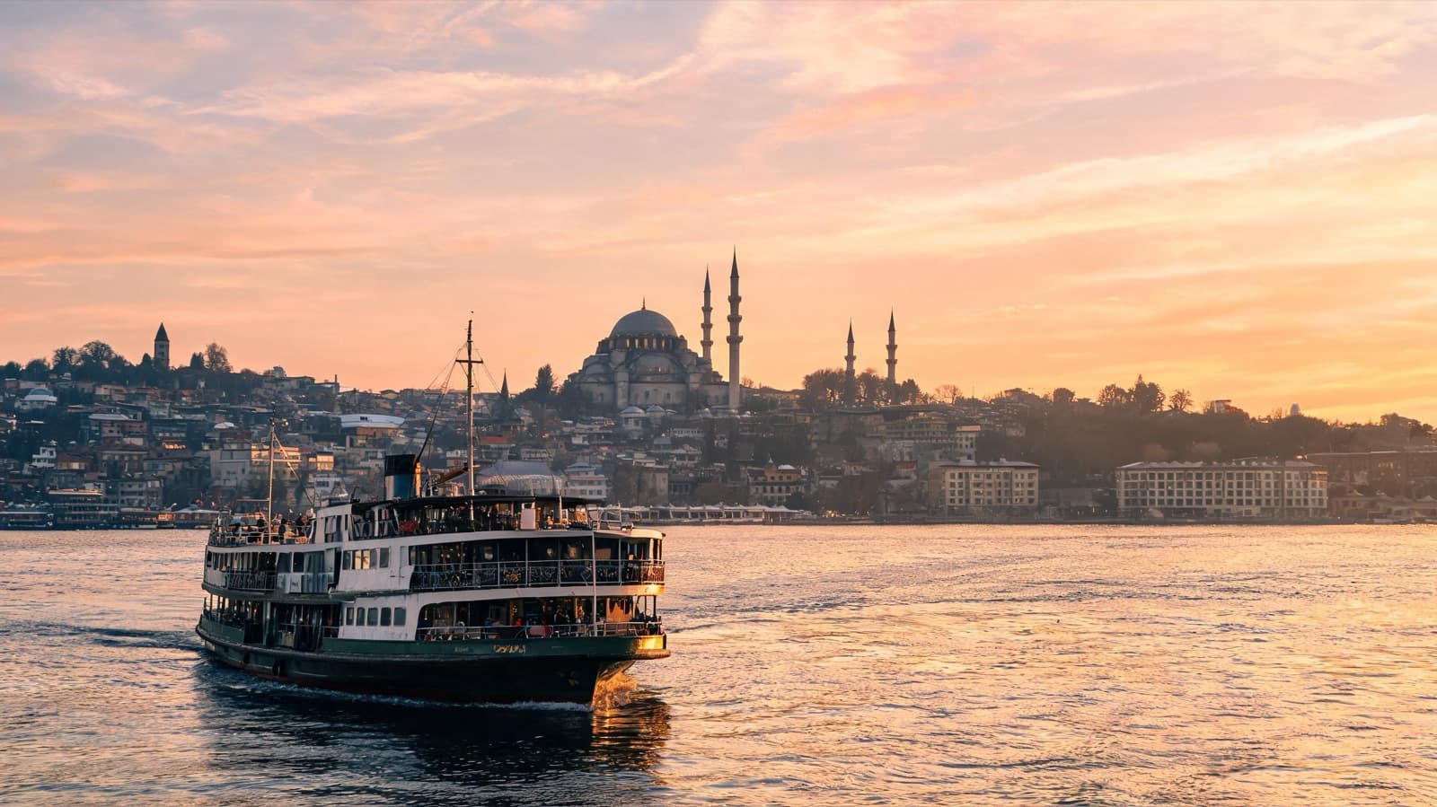 Istanbul skyline with the Süleymaniye Mosque and the Golden Horn at sunset, with a ferry in the foreground