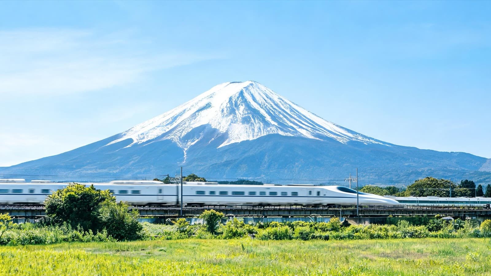 Shinkansen bullet train passing with Mount Fuji in the background on a clear day