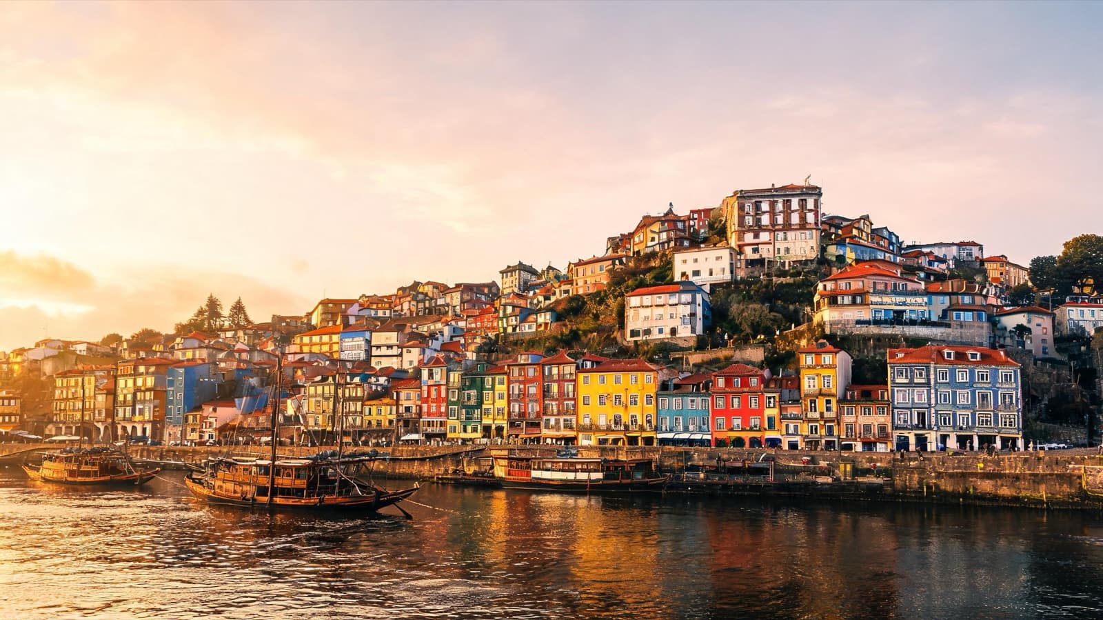 Porto riverside with colorful tiled houses stacked on the hill above the Douro at golden hour